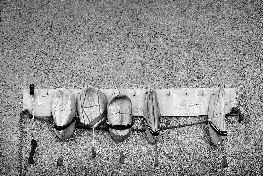 Caps and belts hanging from a board on a wall.